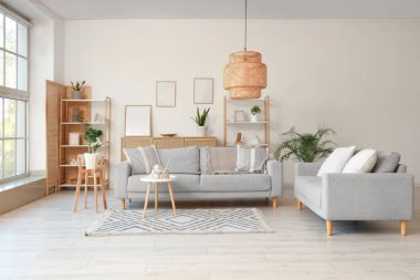 Gri kanepeler, raf üniteleri ve bitkilerle aydınlık oturma odasının içinde.