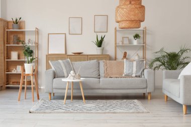 Gri kanepeler, raf üniteleri ve bitkilerle aydınlık oturma odasının içinde.