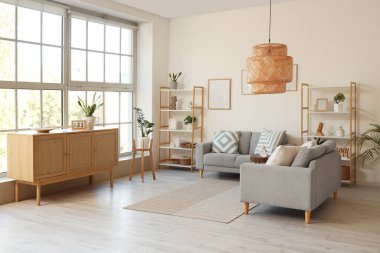 Gri kanepeler, raf üniteleri ve bitkilerle aydınlık oturma odasının içinde.