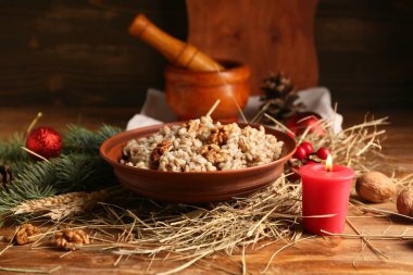 Bir kase geleneksel Ukrayna Kutya tabağı Noel ağacı dalı ve ahşap zemin üzerinde yanan mum.