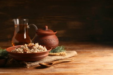 Bir kase geleneksel Ukrayna Kutya yemeği, bir sürahi Uzvar ve tahta arka planda Noel ağacı dalları.