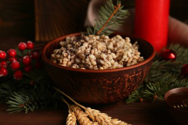 Bir kase geleneksel Ukrayna Kutya yemeği Noel ağacı dalları ve ahşap zemin üzerinde mum