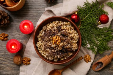 Bir kase geleneksel Ukrayna Kutya yemeği, kozalaklı dallar ve ahşap arka planda yanan mumlar.