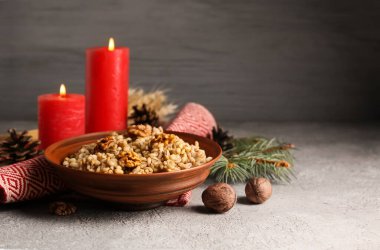 Bir kase geleneksel Ukrayna Kutya yemeği köknar dalı ve beyaz masada yanan mumlar.