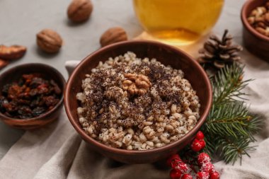 Bir kase geleneksel Ukrayna Kutya yemeği ve gri arka planda çam kozalağı ve Noel ağacı dalı