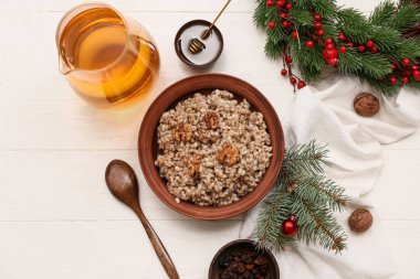 Bir kase geleneksel Ukrayna Kutya yemeği Noel çelengi ve beyaz ahşap arka planda bir sürahi Uzvar.