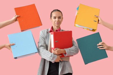 Pembe arka planda klasörleri olan genç iş kadını ve kadın elleri