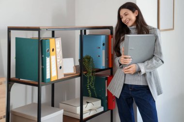 Ofiste rafların yanında klasörü olan güzel bir iş kadını.