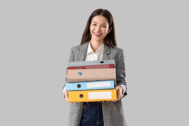 Beautiful businesswoman with folders on light background clipart