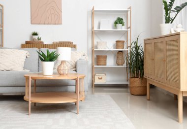 Gri kanepe, masa ve raf ünitesiyle aydınlık oturma odasının içinde.