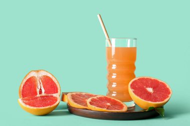 Bir bardak lezzetli greyfurt suyuyla ahşap tabak ve arka planda taze meyve.