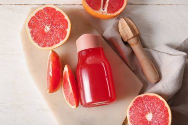 Lezzetli greyfurt suyu, taze meyve suyu ve hafif ahşap arka planda meyve sıkacağı olan bir tahta.