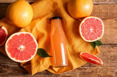 Lezzetli greyfurt suyu, taze meyve ve ahşap arka planda peçete içeren kompozisyon