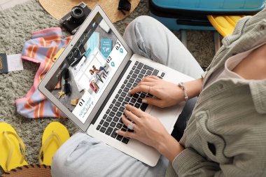 Yeşil halıda plaj aksesuarları olan dizüstü bilgisayar kullanan kadın seyahat blogcusu, yakın plan