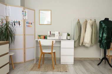 Terzinin iş yeri, katlama ekranı ve kıyafetleri olan atölyenin içi