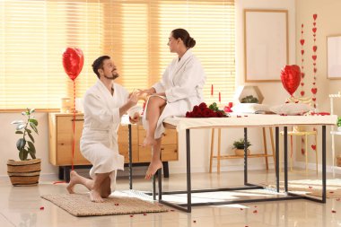 Genç bir adam güzellik salonunda kadının parmağına nişan yüzüğü takıyor. Sevgililer Günü kutlaması