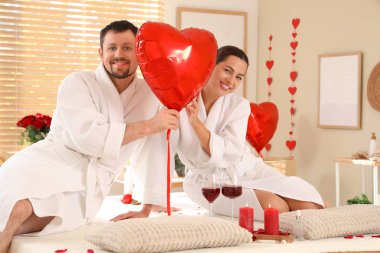 Sevgililer Günü 'nde kaplıca salonunda kalp şeklinde balonları olan genç bir çift.