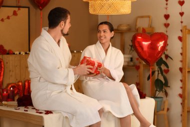 Sevgililer Günü 'nde karanlık kaplıca salonunda hediye kutusu olan genç bir çift.