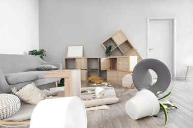 Depremden sonra mobilyaların devrildiği dağınık bir oturma odası.