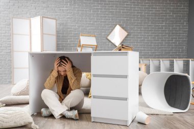 Deprem sırasında evdeki masanın altında saklanan genç kadın.