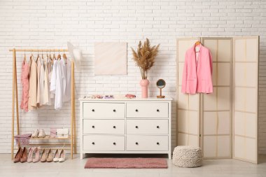 Modern giyinme odasının şık iç mekanı kadın kıyafetleri ve otlarla dolu.