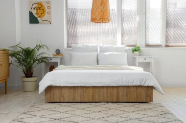 Masalar, palmiye ağaçları ve çalar saatle aydınlık yatak odasının içinde.