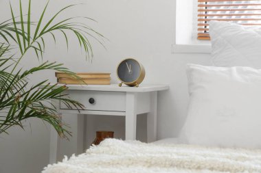 Açık yatak odasındaki masada kitapları olan çalar saat.