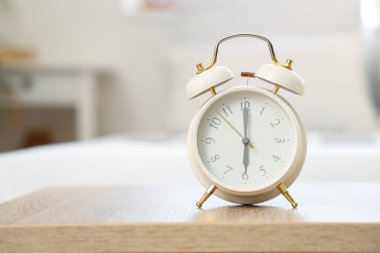 Yatak odasındaki masada beyaz alarm saati, yakın plan.