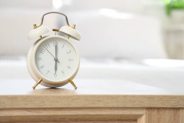 Yatak odasındaki masada beyaz alarm saati, yakın plan.