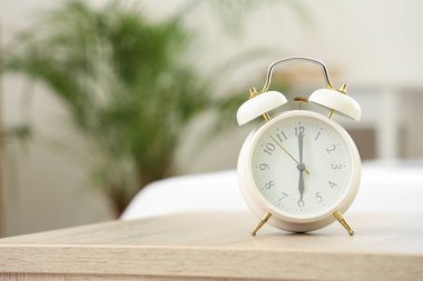 Yatak odasındaki masada beyaz alarm saati, yakın plan.