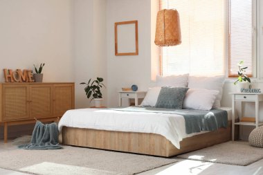 Masalar, çekmeceler ve çalar saatle aydınlık yatak odasının içinde.