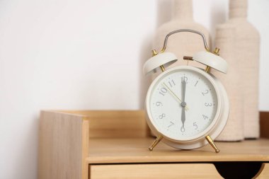 Lamba duvarının yanındaki masada şişe olan çalar saat, yakın plan.