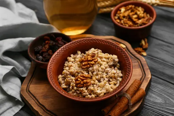Siyah ahşap arka planda ceviz ve tarçınlı geleneksel Ukrayna Kutya yemeği.