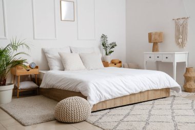 Masaları ve çalar saati olan aydınlık yatak odasının içi.