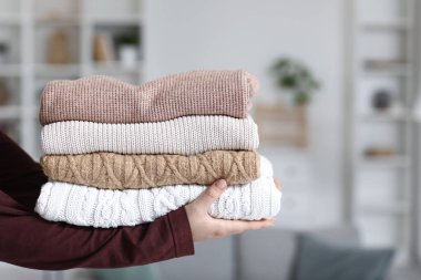 Kadının elinde kışlık giysiler var, yakın plan.