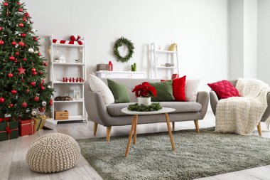 Oturma odasının içinde kanepe, koltuk ve Noel çiçeği süsleri var.