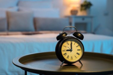 Geceleri karanlık yatak odasındaki masada çalar saat, yakın plan.