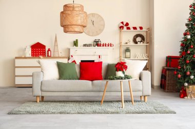 Masanın üzerinde kanepe ve Noel çiçeği süsleriyle aydınlık oturma odasının içinde.