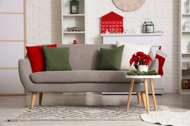 Oturma odasının içinde, kanepe ve Noel çiçekleri olan masa.