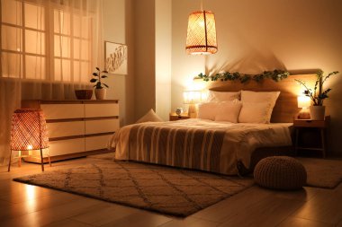 Masaları, çalar saati ve geceleri parlayan lambaları olan karanlık bir yatak odası.