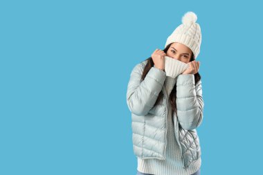 Young woman in winter clothes on blue background