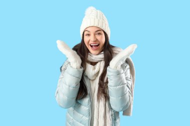 Kış giysileri mavi arka plan üzerinde mutlu genç kadın