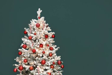 Yeşil duvarın yanında çelengi olan güzel Noel ağacı