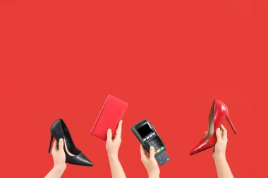 Kırmızı arka planda yüksek topuklu kadın elleri, cüzdanı ve ödeme terminali var. Kara Cuma İndirimi