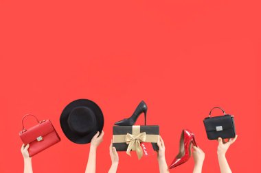 Kırmızı arka planda hediyeli ve aksesuarlı bir kadın eli. Kara Cuma İndirimi