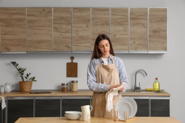 Bulaşıkları peçeteyle temizleyen genç bir kadın.