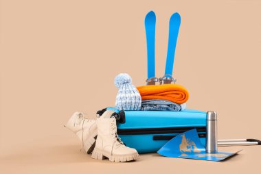 Kış aksesuarları, kayaklar ve bej arka planda harita.