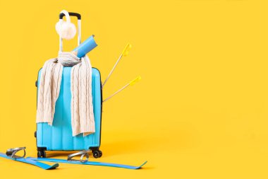 Sarı arka planda kış aksesuarları ve kayak çantaları.