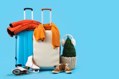 Mavi arka planda kış aksesuarları olan bavullar