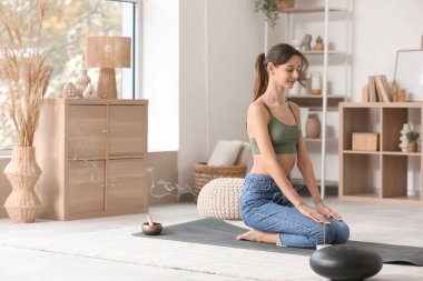 Evde aroma çubuğuyla meditasyon yapan güzel genç bir kadın.
